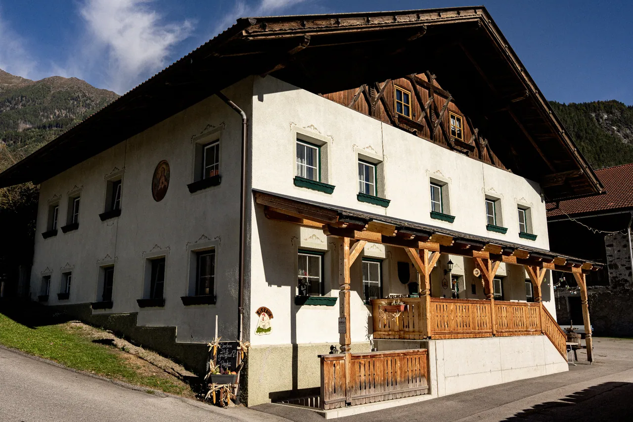 Das Wohnhaus am Binterhof mit Holzveranda und Bergkulisse